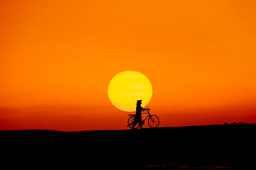 Silhouette Vietnam girl with bicycle   go to travelling with beautiful sun sky background.