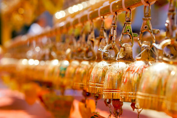 Obraz premium Closeup and perspective view group of small golden bells hang in Thai temple on blurry background.