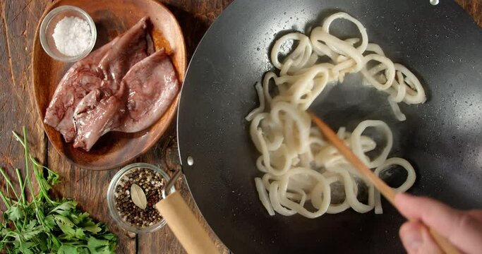 Cooking squid in hot oil. On a wooden background.