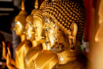 Closeup and crop old and golden face of golden Buddha statue on blurred golden Buddha statue stand...