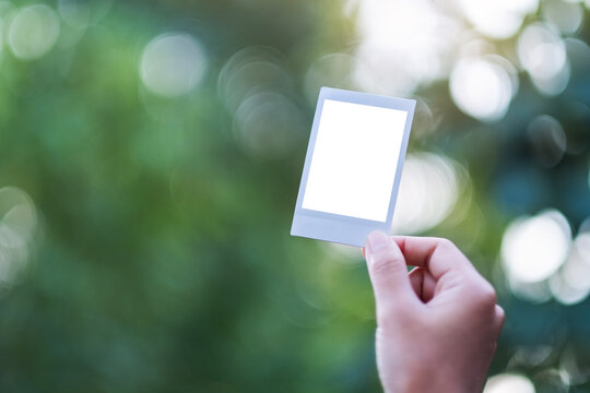 A Hand Holding Mockup Of Polaroid Photo Frame With Blurred Background