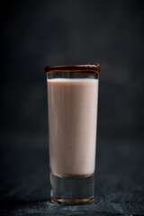 Alcohol cocktail in shot glass with chocolate liqueur and vodka. Selective focus. Shallow depth of field.