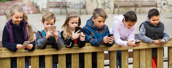 american children posing at urban street with mobile devices