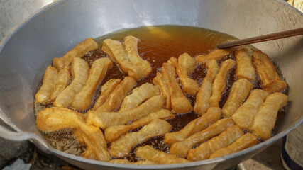close up frying fried bread with a wooden spatula on pan : a traditional of Indonesian street food