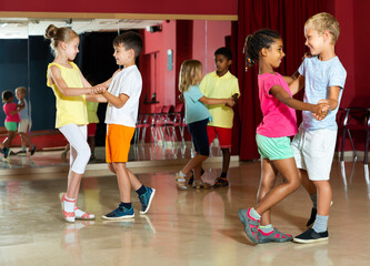 Group of smiling kids dancing salsa dance in modern studio