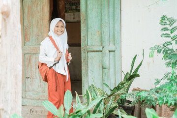 happy indonesian student getting ready to school in the morning standing in front of her house