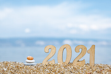 Creative Christmas card. New Year's numbers 2021 on the beach by the sea with a cairn. Selective focus. Copy space.
