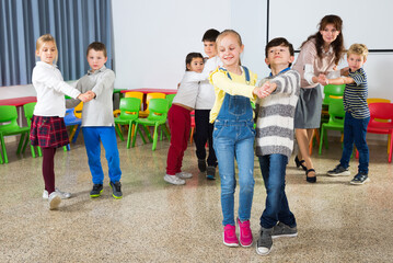 Happy laughing pupils of primary school having fun during break with their teacher, training dance movements