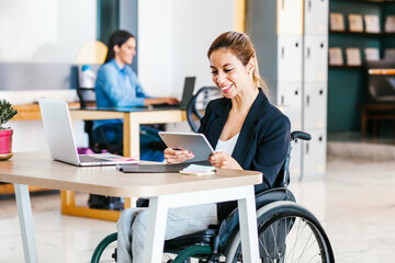 Young latin woman in wheelchair at workplace