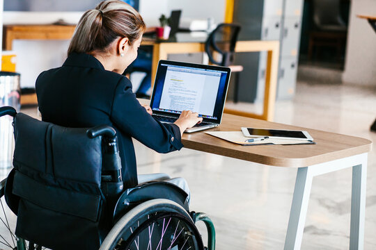 Mexican woman in wheelchair working with laptop in office in Mexico city