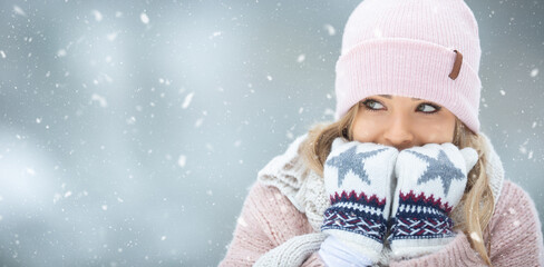 Girl warming her hands in gloves by breathing warm air on them