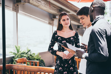 Multiracial friends sitting in cafe enjoying coffee during work break, listening to Caucasian male talking and sharing thoughts, diverse colleagues meeting in coffeeshop discussing business project