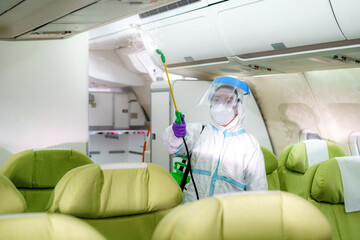 Airline woman staff in Protective suit (PPE) wearing medical face mask disinfecting spray for...
