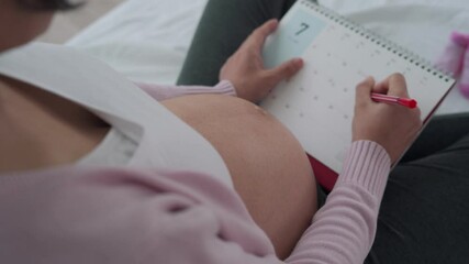 A pregnant woman is making a mark on the due date of birth. Caesarean section is a way for pregnant women to know a due date. Concept of preparing for mother...