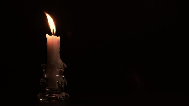 Candlestick holder with burning candle flame on black background, copy space, 4K
