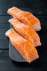 Raw salmon fillets, on black wooden table