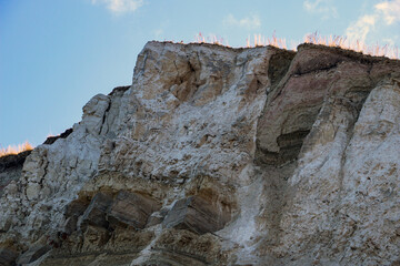 sandy-gypsum cut of the earth in quarry for the extraction of gypsum. Mountain textures of different soil layers with deposits of sand, clay, gypsum, quartz and gypsum ore, after erosion.