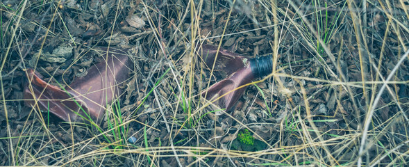 A brown plastic bottle lies on the ground. Environmental pollution concept.