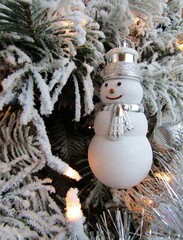 Snowman toy hanging on white Christmas tree