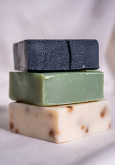 Refreshing handmade soaps made of roses, aloe vera and activated carbon stacked on a white background.