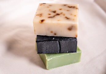 Refreshing handmade soaps made of roses, aloe vera and activated carbon stacked on a white background.