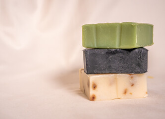 Refreshing handmade soaps made of roses, aloe vera and activated carbon stacked on a white background.