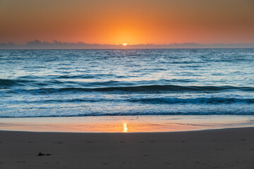 Hazy sunrise seascape with low swell
