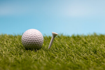 Golf ball is on green grass with blue sky background