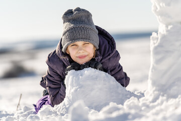 Fototapeta na wymiar Close up portrait of a happy little girl playing with snow in park on white snow background