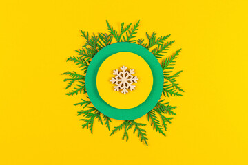 Christmas composition with coniferous tree branches on yellow paper background. Round frame of Christmas tree branches and decorations with space for text. Top view. New year concept