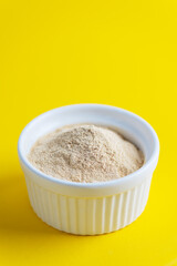 Lecithin powder in a bowl on a yellow background.