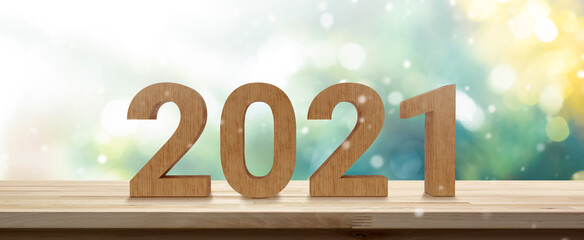 2021 numbers on wood table top in green and gold shinny banner background