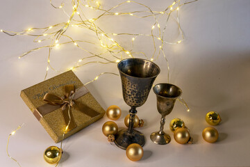 golden cups, golden glass balls and various Christmas decorations, illuminated background of a chain of white lights