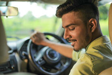Young indian man driving a new car
