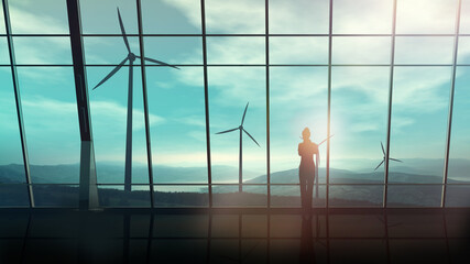 In a spacious room against the window, a business woman looks at wind turbines.