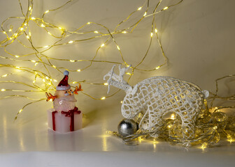 white crocheted deer Rudolph, Santa Claus and various Christmas decorations, illuminated white light chain background, Christmas waiting time, winter
