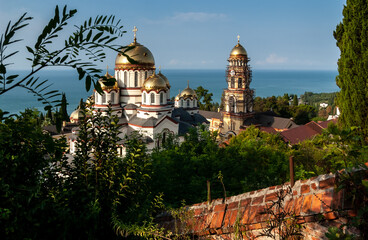 Male Simon the Conanite Monastery Golden domes, orange brick fence, lush greenery and endless blue sea. New Byzantine style 1875. New Athos, Abkhazia.