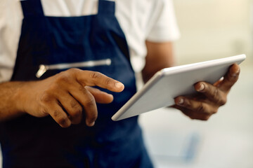 Obraz premium Close-up of mechanic working on digital tablet in auto repair shop.