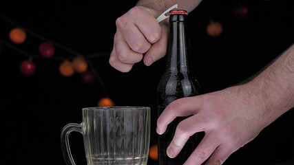 A dark brown bottle with a red cap stands on a wooden table, behind a dark background