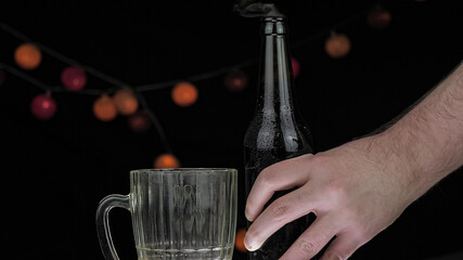 A dark brown bottle with a red cap stands on a wooden table