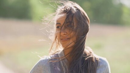 slow motion portrait of beautiful carefree young beautiful smiling mixed race woman walks outdoors at sunny autumn day. brunette girl with blowing hair by wind - Powered by Adobe