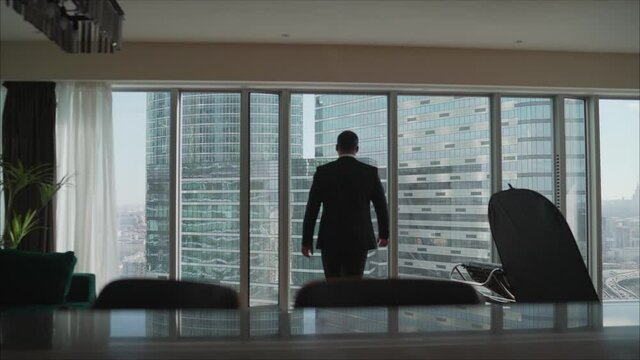 Confident businessman in a large modern office. A modern building. The businessman comes up to the window.