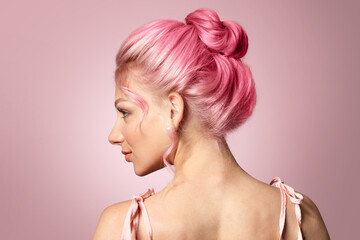 Beautiful young woman with unusual hair on pink background
