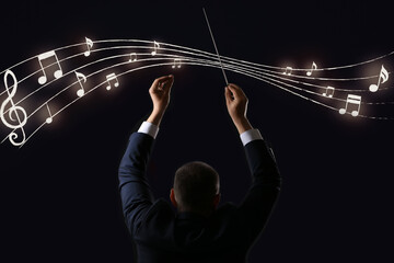 Male conductor and note signs on dark background