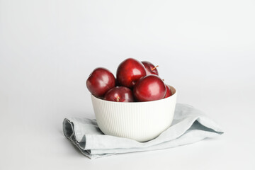 Fruit bowl with  fresh ripe plums on white background