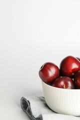 Fruit bowl with  fresh ripe plums on white background