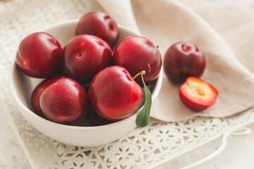 Bowl with  fresh ripe plums on  table