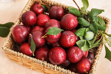 Wicker basket with fresh ripe plums on table