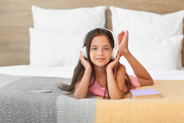Cute little girl listening to music in bedroom