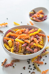 Bowl with uncooked pasta on light background